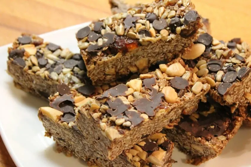 Barras caseras con avena, cacahuate, semillas de girasol y chispas de chocolate, apiladas en un plato blanco
