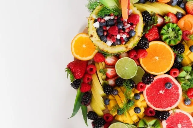 Composición circular de frutas frescas troceadas: piña, kiwi, fresas, arándanos y cítricos