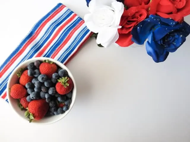 Cuenco blanco con fresas y arándanos frescos sobre un mantel de rayas