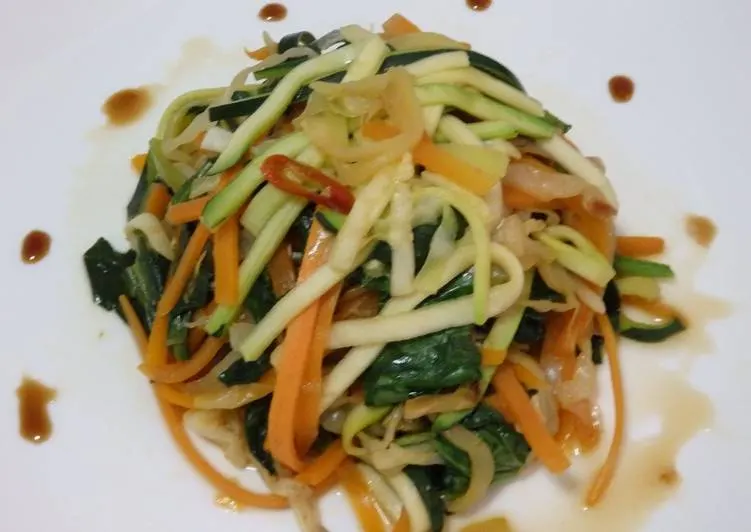 Tallarines de calabacín y zanahoria salteados, servidos en un plato blanco