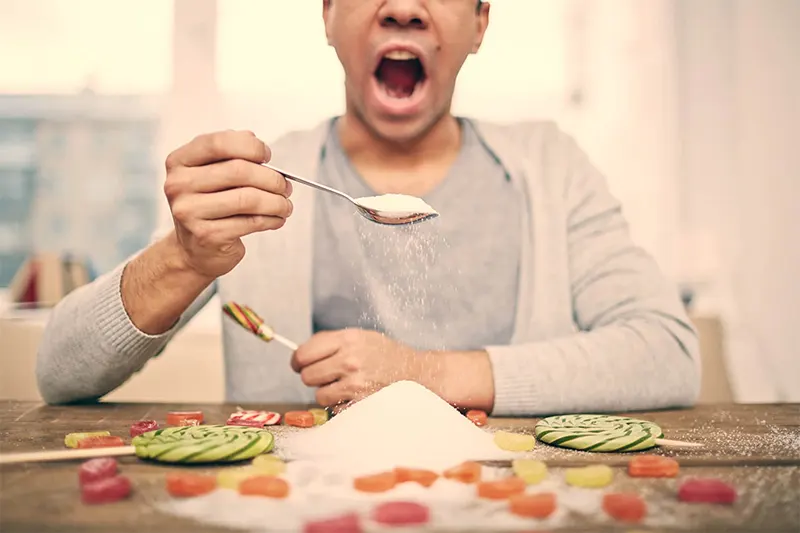 Hombre llevándose a la boca una cucharada de golosinas y dulces