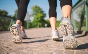 Primer plano de los pies de dos personas caminando con zapatillas por un paseo