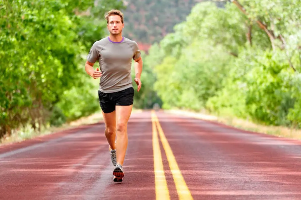 Hombre corriendo por una carretera rodeada de vegetación