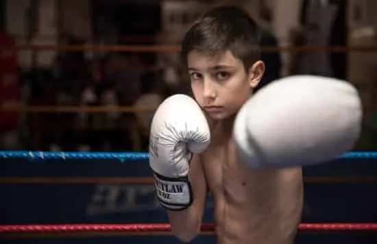 Niño con guantes de boxeo lanzando un directo dentro de un ring
