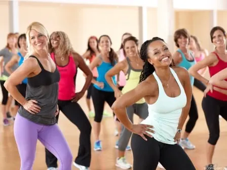 Clase de baile fitness con un grupo de mujeres sonriendo mientras se ejercitan