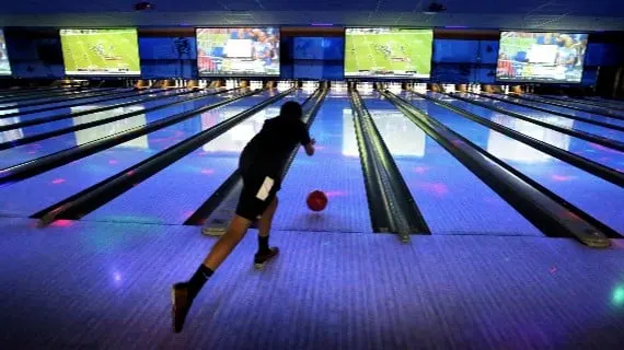 Jugador de bowling lanzando la bola por la pista