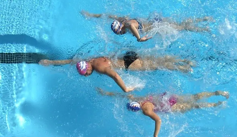 Tres nadadores avanzando a crol por las calles de una piscina