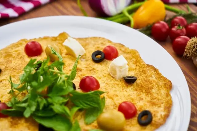 Tortilla de claras con espinacas, tomate y aceitunas en un plato