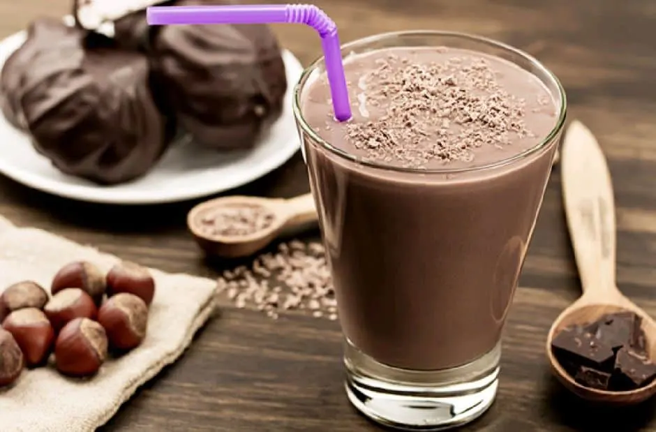 Vaso de batido de chocolate con avellanas y galletas al lado