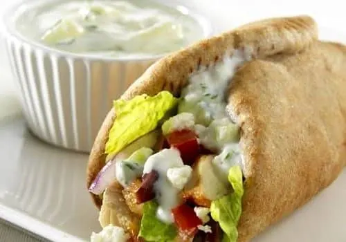 Pan de pita relleno de verduras y pollo con salsa de yogur al lado