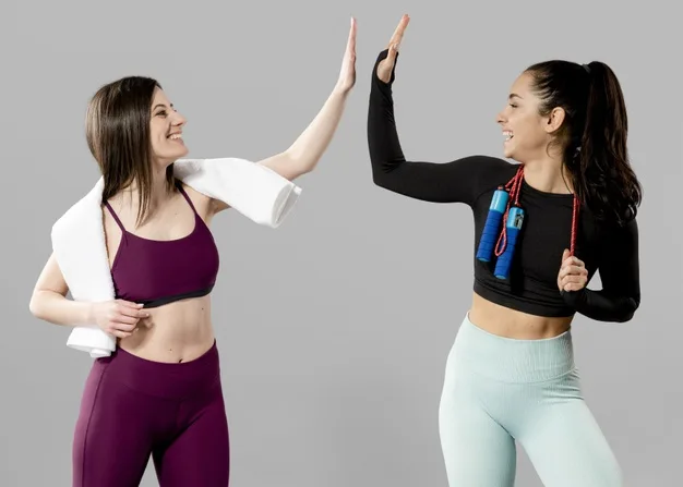Dos mujeres chocando las manos en alto después de entrenar