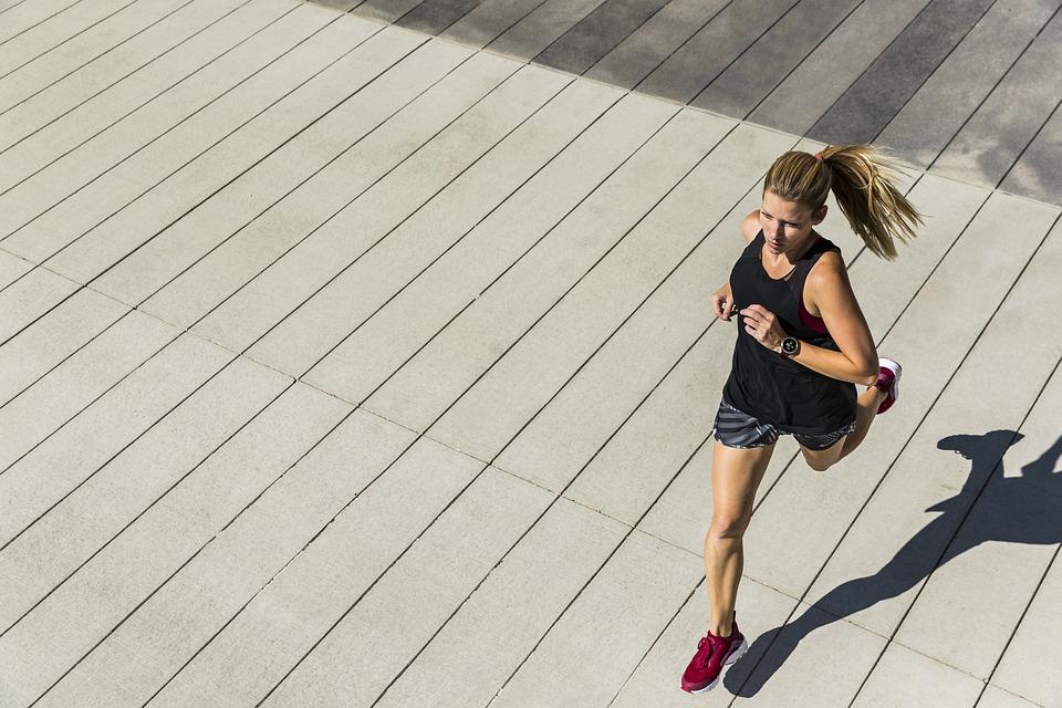 Mujer corriendo vista desde arriba, con su sombra proyectada en el suelo
