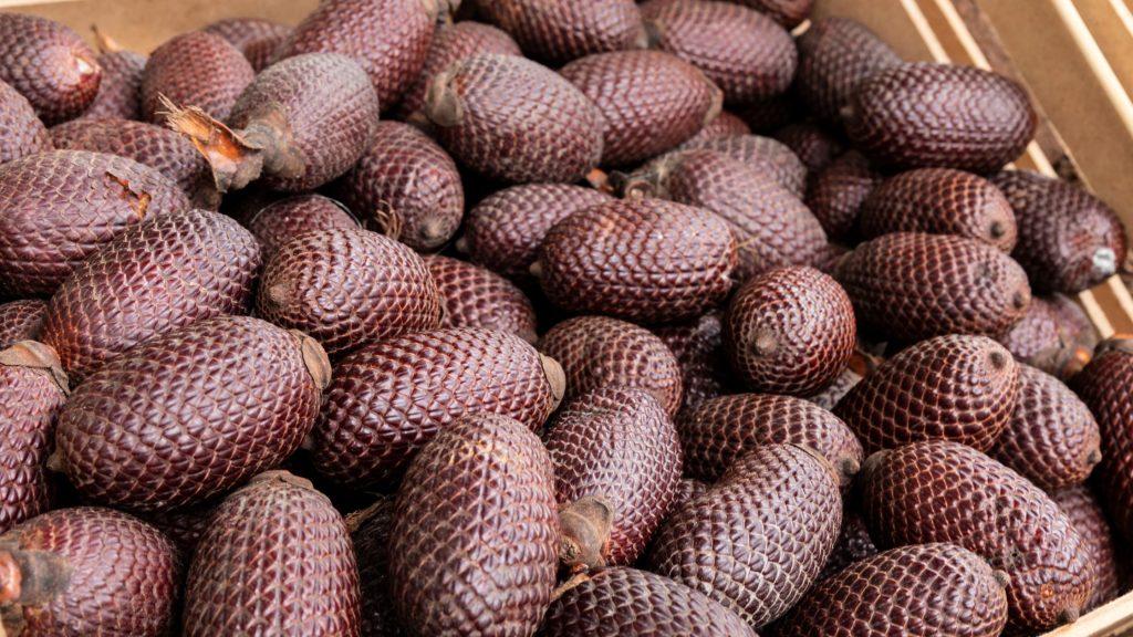 Frutos de aguaje amontonados, con su cáscara rojiza y escamosa