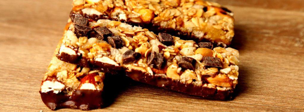 Barras de proteína caseras con avena, almendras y trozos de chocolate sobre una tabla de madera